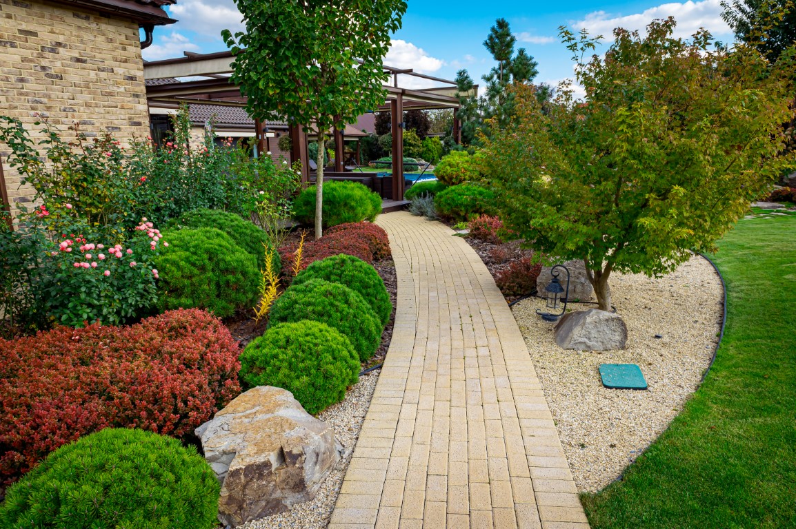 Front yard, landscape design with multicolored shrubs intersecting with bright green lawns behind the house is a modern, garden care service, green grass with a beautiful yard for the background.